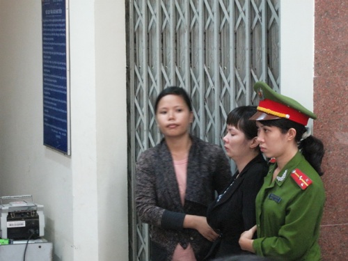 Bà Nguyễn Thị Lệ Đông (giữa) được đưa đến nơi làm việc để khám xét.