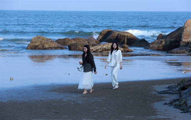 Hai du khách hiếm hoi đi bộ trên bãi biển vắng...