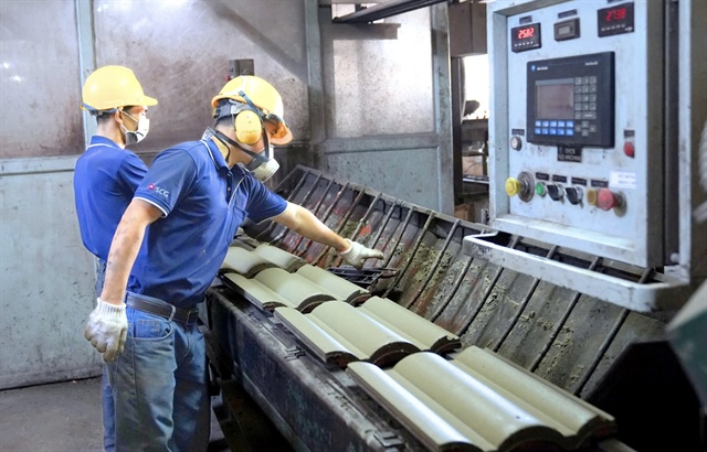 Many firms are focusing on manufacturing green building materials to reduce carbon dioxide emissions. The photo shows employees at work at a factory in Binh Duong Province, southern Vietnam producing Singapore-green certified roof tiles. Photo: SCG