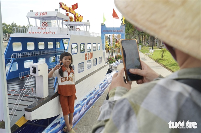 A girl poses for a photo with a miniaturized 100-metric-ton ferry, part of the Hu Tieu My Tho festival in Tien Giang Province, which runs until December 31, 2024. Photo: Mau Truong / Tuoi Tre