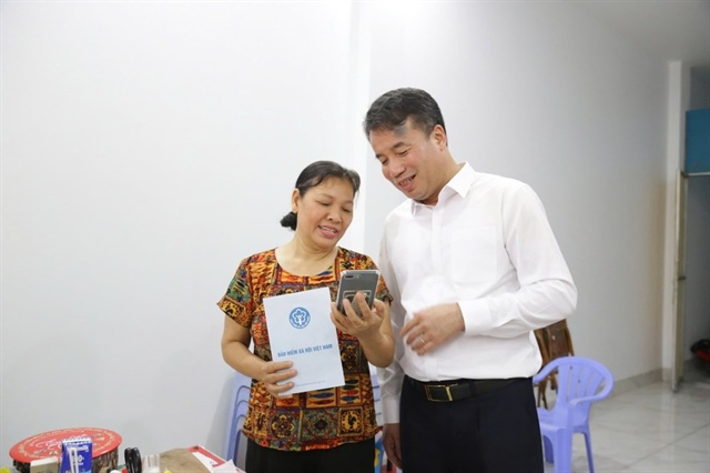 Lãnh đạo BHXH Việt Nam (áo trắng) kiểm tra việc chi trả lương hưu cho người dân qua tài khoản cá nhân. Ảnh minh họa: P.PHONG